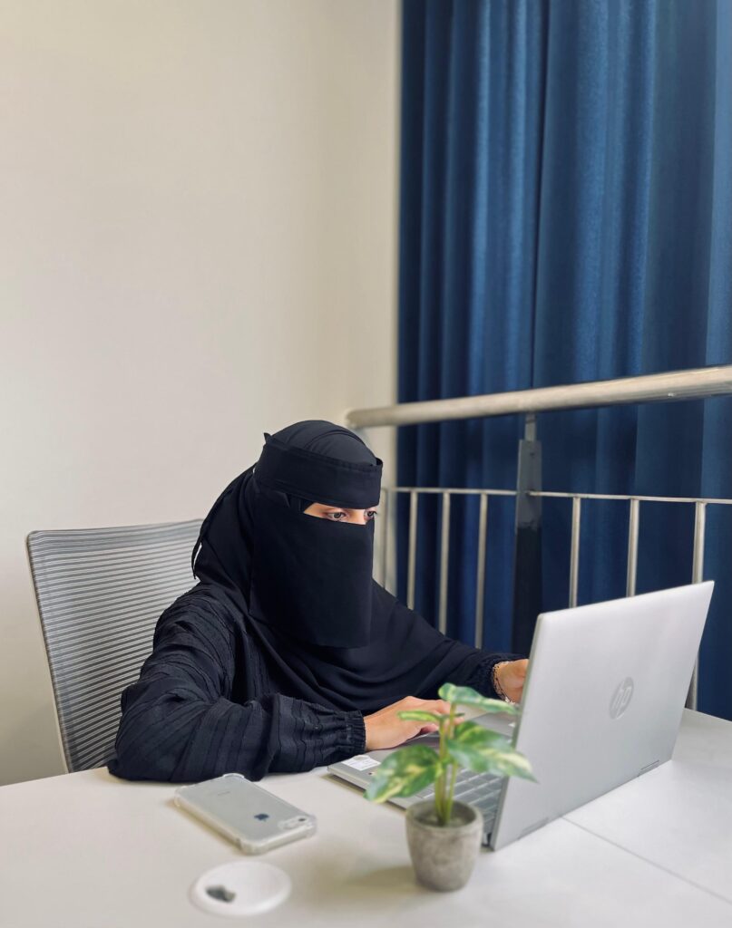 A professional freelance digital marketing consultant in malappuram woman, in a black abaya and niqab working on a laptop at a modern office desk, symbolizing focus, productivity, and digital expertise.